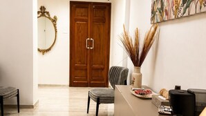 A modern reception area with a marble floor, a wooden door, a mirror, a desk with a coffee machine, and a decorative plant. - Valentina Rooms – Elegant Stay in Bronte, Pistacchio e Etna. (Bronte)