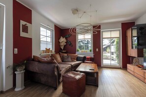 Ein Wohnzimmer mit braunem Ledersofa, einem Holztisch und einer roten Akzentwand.