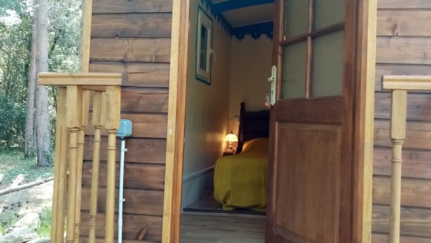 Een houten hutje met een houten trap die leidt naar een bed met een gele deken.
