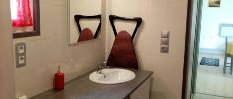 A bathroom with a sink, mirror, red towel, and a washing machine.