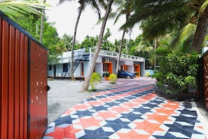 A building with a staircase leading to a door, surrounded by palm trees and a patterned walkway.