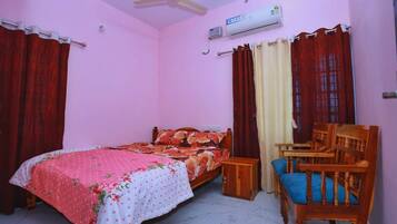 Un dormitorio con una cama, una silla, un equipo de aire acondicionado y cortinas.
