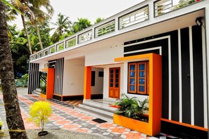 A modern building with a white facade, black and orange accents, and a checkered tile entrance.