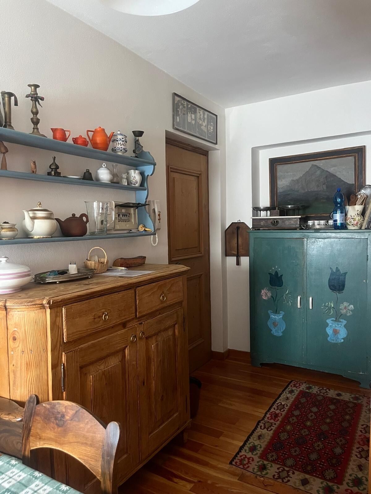 A kitchen with wooden cabinets, a dining table, and a blue cabinet with floral designs.