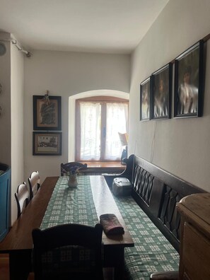Ein Essbereich mit Tisch, Stühlen, einer Bank und gerahmten Bildern an der Wand.