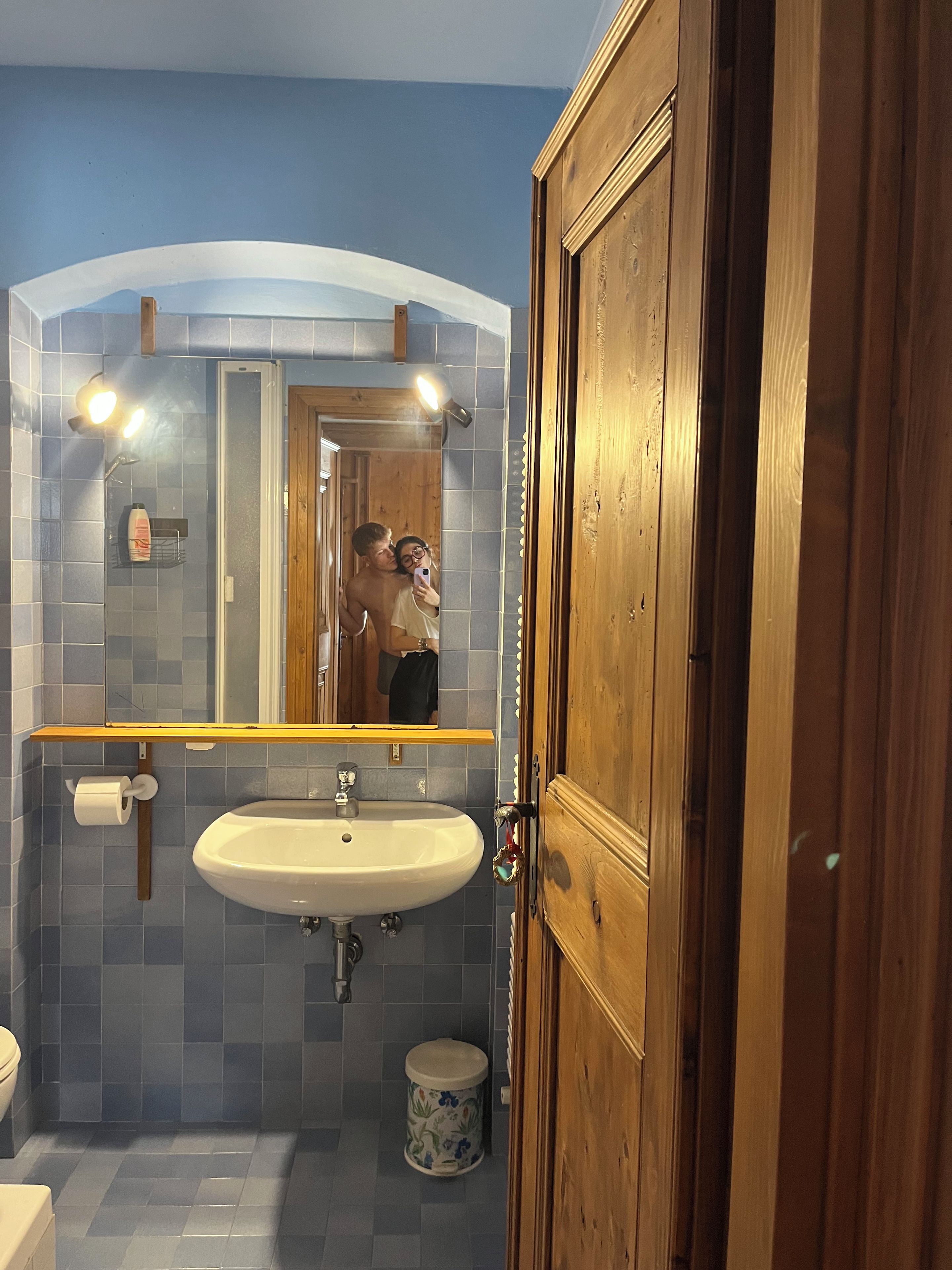 A bathroom with a sink, mirror, and wooden door.