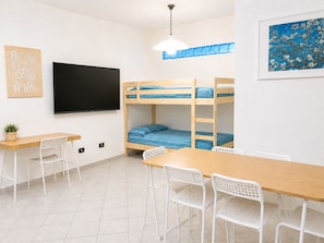 A room with bunk beds, a desk, chairs, a TV, and a painting. - SMART EMERALD COAST (provincia della gallura nord-est sardegna)