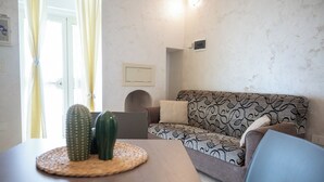 Een woonkamer met een gestreept bankstel, een tafel met een geweven placemat en een cactus op tafel.