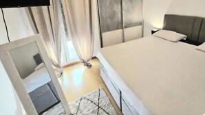 Un dormitorio con una cama, un televisor montado en la pared, una puerta corredera y un equipo de aire acondicionado.