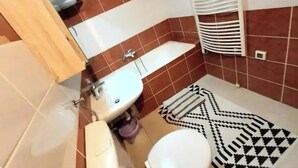 Un baño con lavamanos, inodoro y toallero.