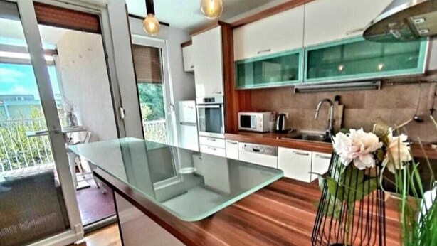 Una cocina moderna con una isla de vidrio, encimeras de madera y vistas al exterior.