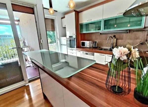 Eine moderne Küche mit einer Glasinsel, Holz Arbeitsplatten und Blick ins Freie.