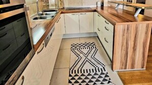 Una cocina moderna con horno integrado, pileta de acero inoxidable y encimera de madera.