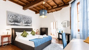 Une chambre à coucher comprenant un lit, des tables de chevet, un bureau, une chaise, un miroir et des œuvres d’art accrochées au mur.