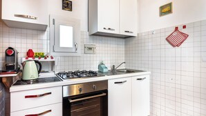 Une cuisine moderne avec des meubles blancs, une cuisinière à gaz, un four et un évier.