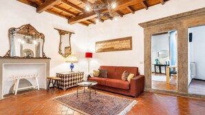 Un salon avec une cheminée, un canapé, une table basse et un tapis à motifs.