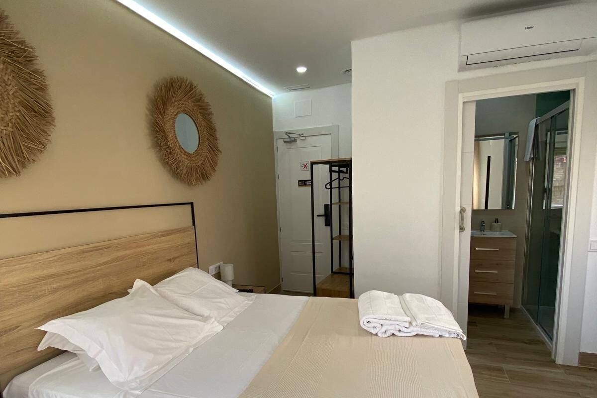 A neatly made bed with a wooden headboard, a ceiling fan, and a wall-mounted mirror.