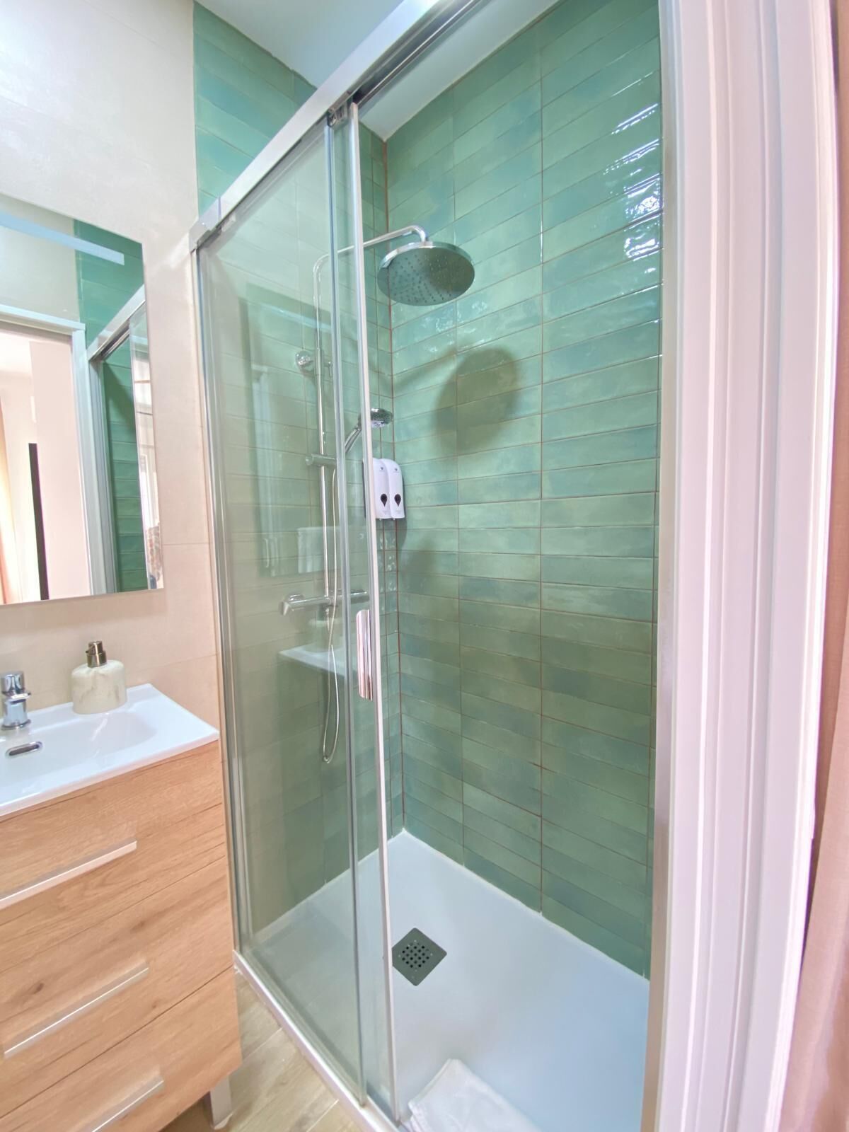 A modern bathroom with a glass-enclosed shower, a vanity with a mirror, and a sink.