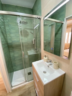 A modern bathroom with a glass-enclosed shower, a white sink, and a wooden vanity.
