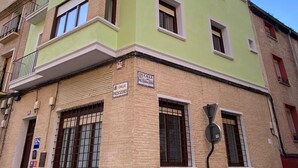Un edificio de varios pisos con fachada verde, numerosas ventanas y un letrero que indica una oficina postal.