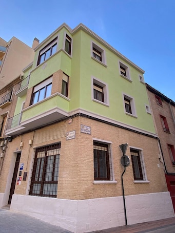 Un edificio a più piani con facciata verde, numerose finestre e una targa che indica la presenza di un ufficio postale.. Grampy Boutique Hostal - Zaragoza Centro