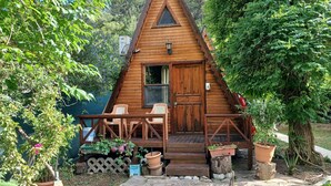 Una cabaña de madera con un porche, una puerta y una ventana.