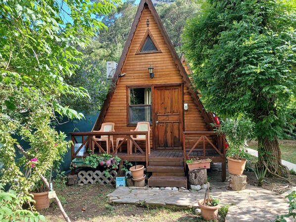 A wooden cabin with a porch, a door, and a window.