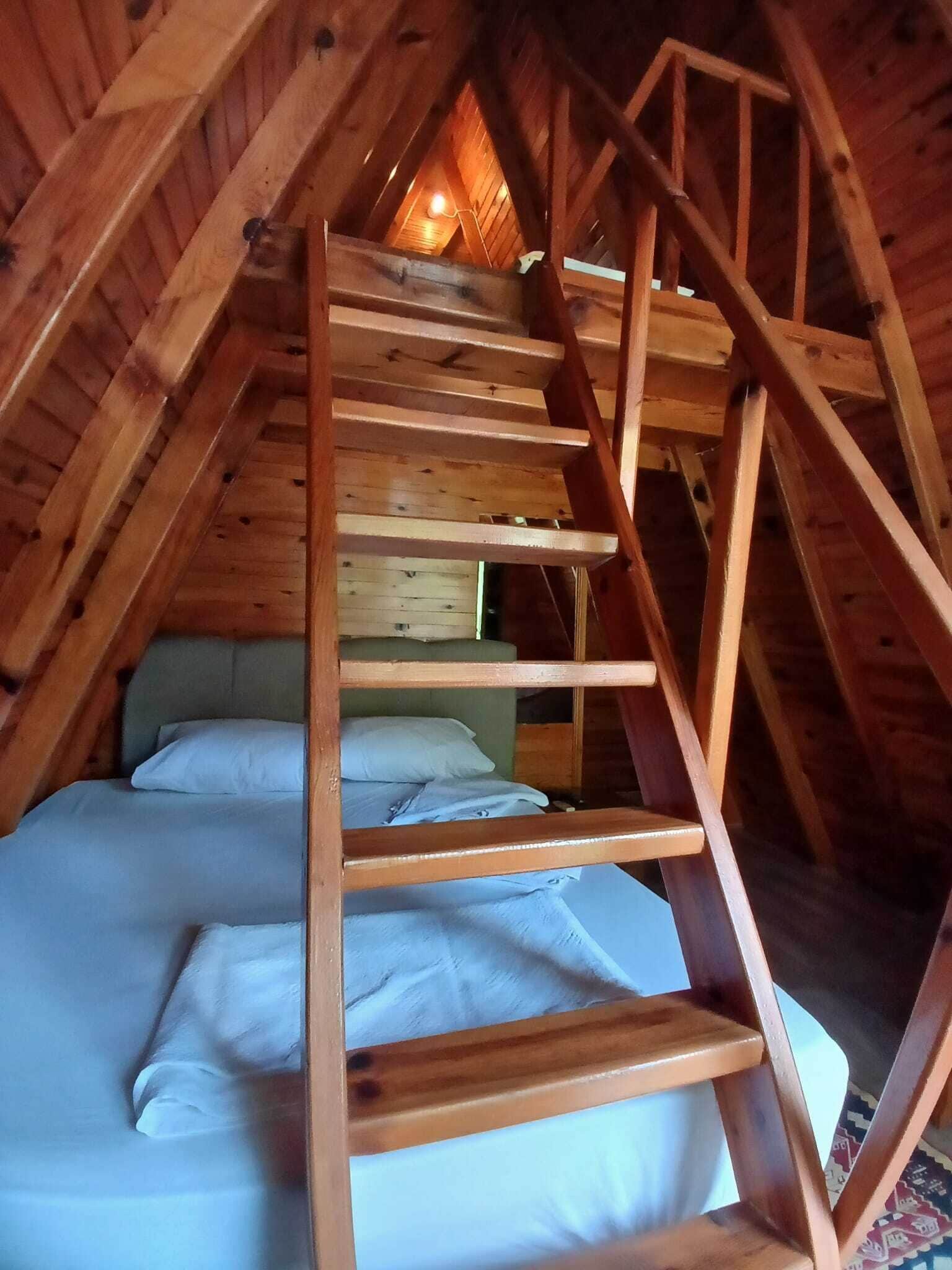 Un dormitorio tipo loft de madera con literas y una escalera de madera.