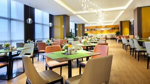 A spacious restaurant with multiple dining tables and chairs, large windows, and a modern ceiling design. - Hampton by Hilton China (Nanchang)