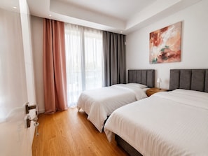 Une chambre d’hôtel avec deux lits, un tableau au mur et une fenêtre avec des rideaux.