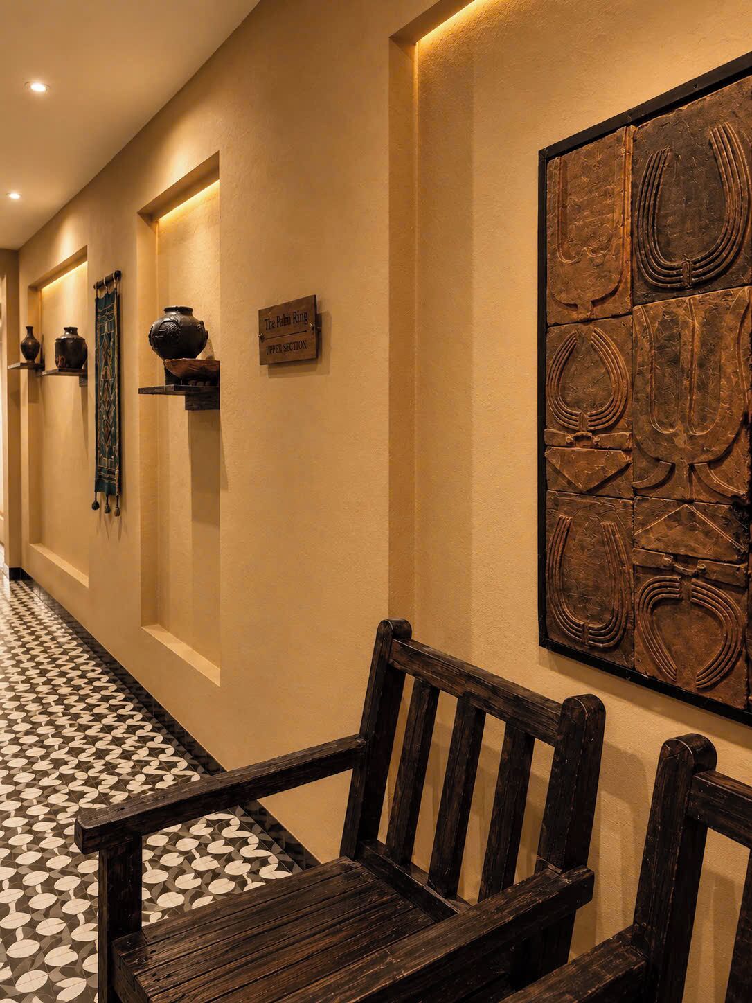 A hallway with a bench, wall-mounted artifacts, and a patterned floor.