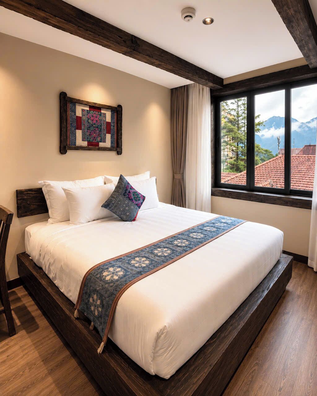 A hotel room with a large bed, a view of mountains, and a wooden ceiling.