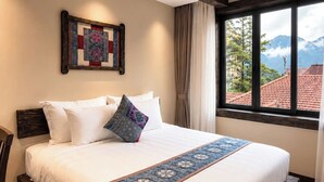 Habitación de hotel con una cama grande, vista a las montañas y techo de madera.