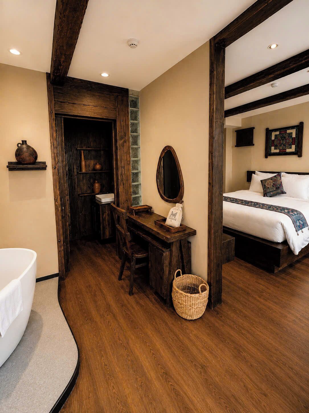 A bedroom with a bed, a bedside table, a mirror, and a wall-mounted quilt.