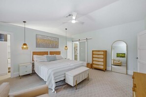 A bedroom with a bed, bedside tables, a bench, a wardrobe, a ceiling fan, and a mirror. - 4BR Marco Island home with heated pool, WiFi, and room for 8 (Marco Island)