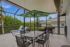 A covered outdoor patio with a table and chairs, a grill, and a basketball hoop. - 4BR Marco Island home with heated pool, WiFi, and room for 8 (Marco Island)