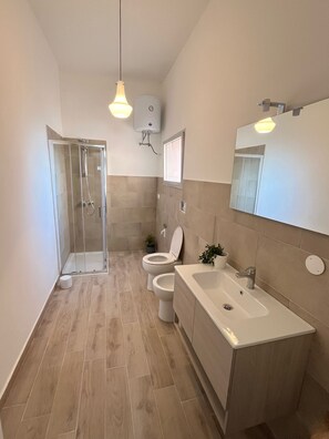 A bathroom with a shower, toilet, sink, and a mirror. - Spacious and bright apartment in the center of Torre dell'Orso with private parking space (Torre dell'Orso)