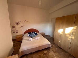 Ein Schlafzimmer mit Bett, Holzschrank und Wanddekorationen.