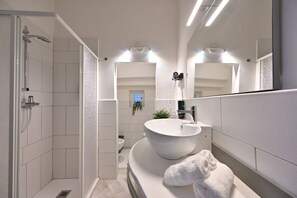 Uma casa de banho moderna com chuveiro de entrada direta, uma pia grande e um espelho.
