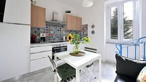 Een moderne keuken met een witte tafel, een vaas met zonnebloemen en een blauwe metalen trap.