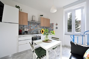 Eine moderne Küche mit einem weißen Tisch, einer Vase mit Sonnenblumen und einer blauen Metalltreppe.