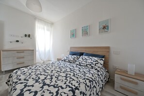 Quarto com cama, mesas de cabeceira, cômoda e obras de arte na parede.