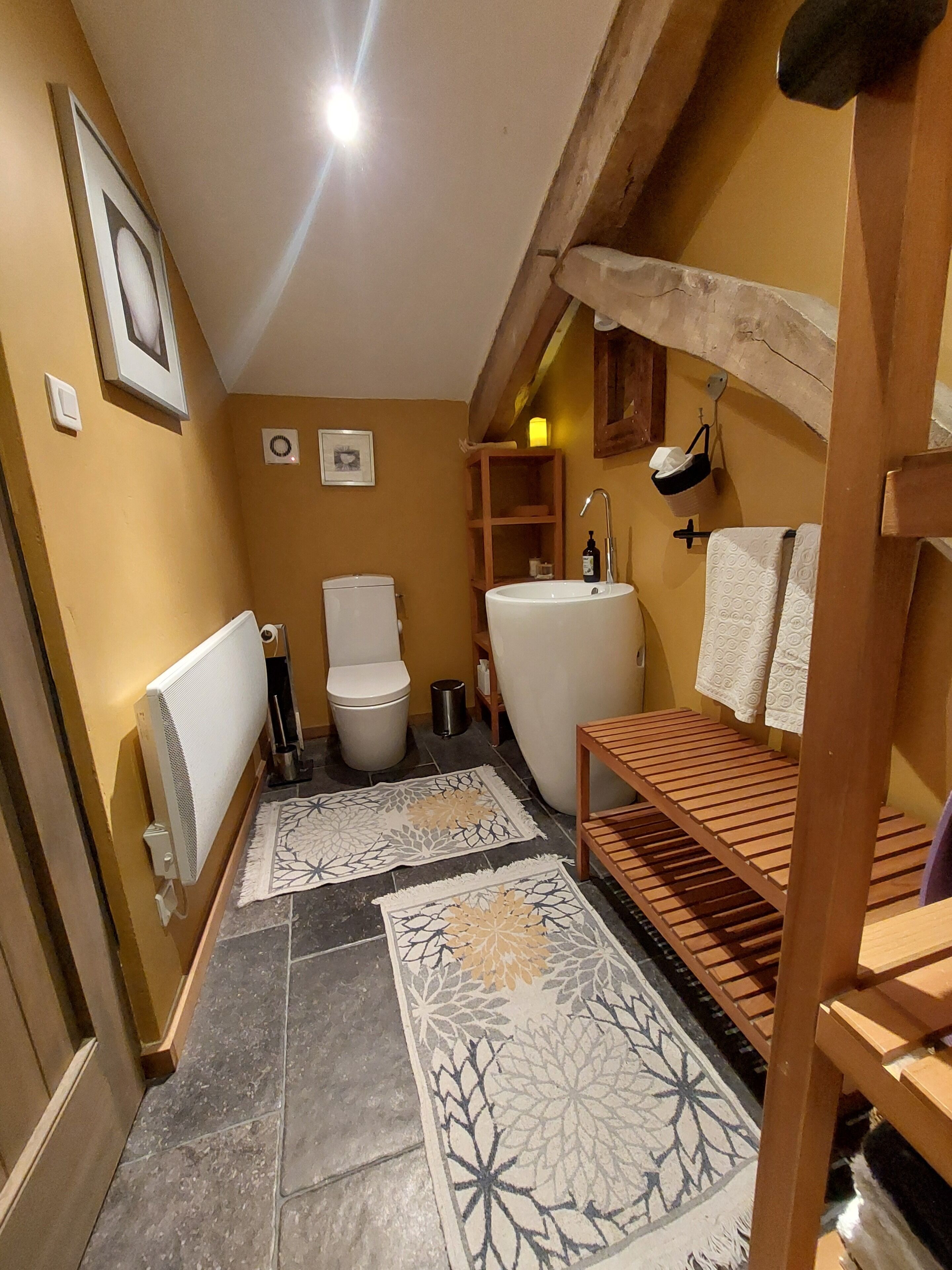 Ein kleines Badezimmer mit Toilette, Waschbecken und einer Holzbank.