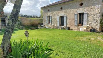 A stone building with a grassy yard, a statue, and a hanging lantern.