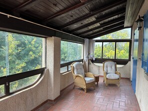 A covered outdoor seating area with wicker chairs and a brick floor. - Country house with 2 apartments, 15 km from Vaison-la-Romaine, with a view of Mont Ventoux, (Travaillan)