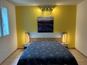 A bedroom with a bed, two bedside tables, a nightstand, a window, and a painting on the wall. - Country House 2 apartments 15 kms from Vaison le Romaine facing Mont Ventoux, (Travaillan)