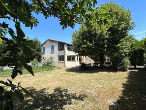 Ein zweistöckiges Haus mit einem großen Baum im Garten.