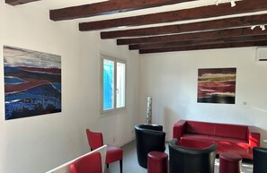 A room with a red sofa, black ottoman, and a painting of a landscape. - Country House 2 apartments 15 kms from Vaison le Romaine facing Mont Ventoux, (Travaillan)