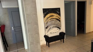 A hallway with a black bench, a large abstract painting on the wall, and a door leading to another room. - Country House 2 apartments 15 kms from Vaison le Romaine facing Mont Ventoux, (Travaillan)