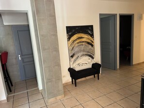 A hallway with a black bench, a large abstract painting on the wall, and a door leading to another room. - Country House 2 apartments 15 kms from Vaison le Romaine facing Mont Ventoux, (Travaillan)
